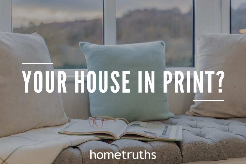 An open magazine with an eyeglass on top of it in a very comfortable sofa with 3 pillows near a breathtaking view of a mountains by a window