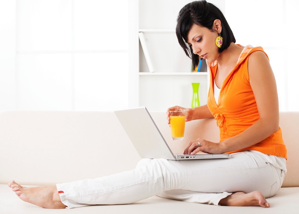 A woman sitting on a couch while looking at her laptop