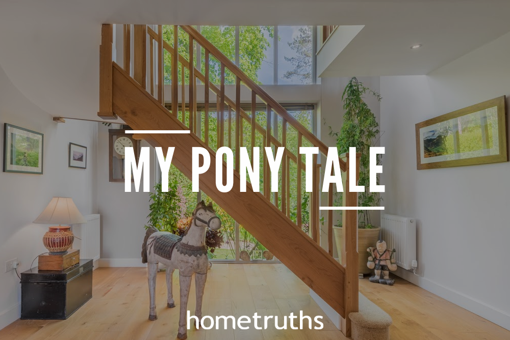 A pony toy underneath a wooden staircase in a friendly bright room with glass windows overlooking the trees outside